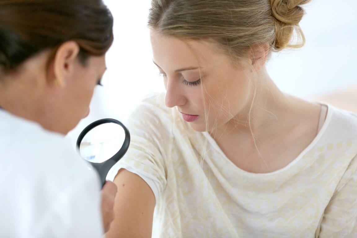 woman at the dermatologist office looking for signs of skin cancer